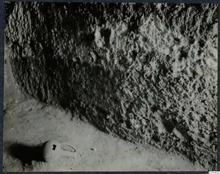 Rock-cut tomb wall at Ayios Iakovos with a small vessel lying on the floor in front of it