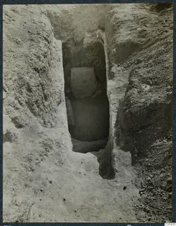 Tomb 10 at Ayios Iakovos: excavated cut leading down to a tomb chamber with a large stone block inside.