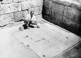 John Lindros crouching beside the large plan of the Vouni palace laid out on the ground between stone walls.