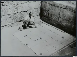 John Lindros kneeling beside the large plan of the Vouni palace, pieced together from paper sheets on the ground.