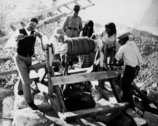 Men operating a wooden winch over a well at Vouni, with a man being lowered into the shaft
