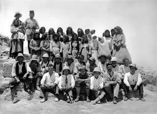 Group photograph of the work force posed on stone blocks at Vouni, with women in headscarves, men in hats and a small child.