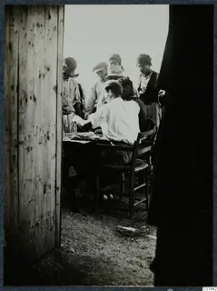 Payment at Vouni: a seated man at a table with papers, watched by standing men in caps and headscarves.