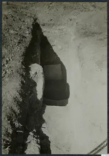 Tomb 4 at Ayios Iakovos: a stone slab in the opening of a tomb chamber in an excavation trench.