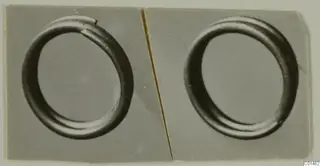 Two plain ring-shaped objects shown side by side in grey-toned photographs mounted on a card