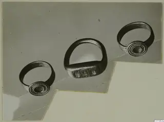 Three rings with round and rectangular bezels, photographed together on a grey mount.