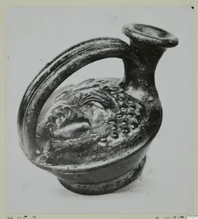 Black glazed pottery vessel with a strap handle and raised relief decoration, from the Marion tombs 31–45 series