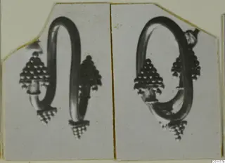 Two views of a gold earring with a looped wire and beaded cone-shaped ends, mounted side by side on a card