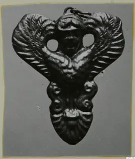 Gold pendant with a central face between two wing-like forms, with a suspension loop at the top