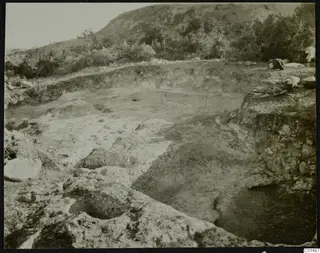 Excavation at Nitovikla on the Karpas Peninsula, with cut rock, a trench and digging tools on the ground