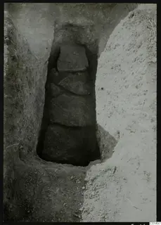 Narrow excavation trench at Kountoura Trachonia with a stacked column of large flat stones at its base.