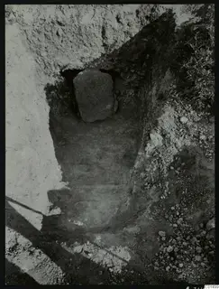 Excavation cutting at Kountoura Trachonia with a large upright stone slab set in a dark recess at the back