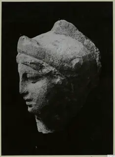 Carved stone head fragment with a band across the brow and downcast eyes, shown against a black background