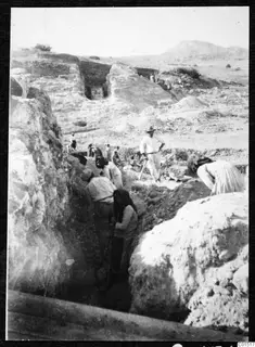 Excavation trench at the theatre at Soli, with workers digging among large stones and a standing man in a hat.