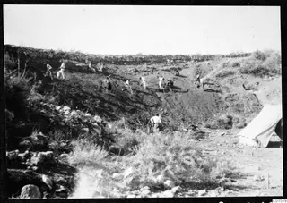 Excavation of the theatre at Soli, with workers digging a slope beside a white tent at right