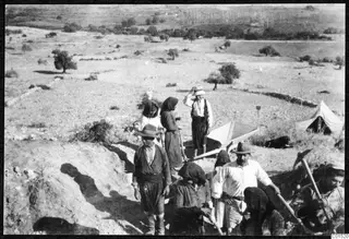 Workers digging in an excavation trench at Soli, with a tent and tools on the slope