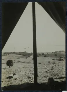 View through a tent opening over scrubland, trees and the sea at Soli