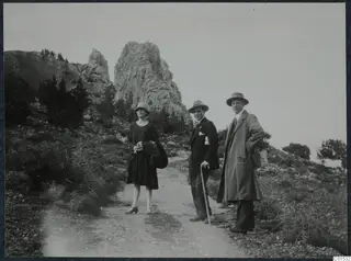 Three people standing on a dirt path below rocky crags at St. Hilarion.