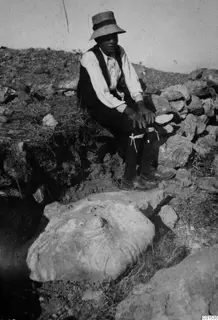 Seated man in a wide-brimmed hat beside a large pale stone block lying in situ at Vouni