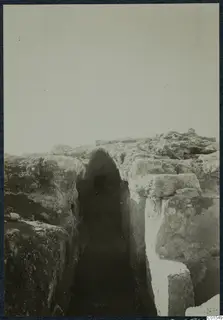 Excavated cutting between large stone blocks, leading to an arched opening at Vouni palace