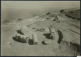 Finds in situ at Vouni with stone blocks, a column drum and a ladder-like frame on a hilltop above the sea.