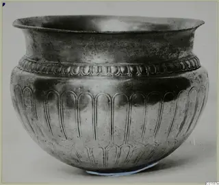 Silver bowl with a wide rim, a band of raised beads below the rim and lobed vertical decoration on the body.