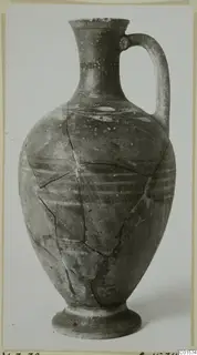 Pottery jug with a single loop handle and pale painted bands, with cracks across the body