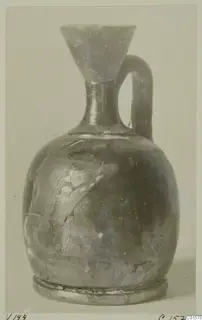 Pottery jug with a funnel mouth, a single loop handle and a ring foot, shown against a pale background