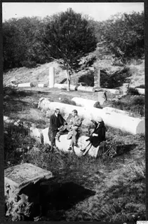 Three people seated on a fallen column drum among scattered column pieces and trees at Salamis, Famagusta