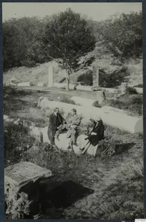 Three people sitting on a fallen column drum among scattered column fragments at Salamis, Famagusta.