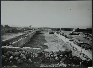 Excavated walls of rough and dressed stone at Vouni palace, with a cleared earthen floor between them.