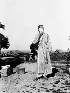Alfred Westholm shaving outdoors at Vouni, wearing a striped housecoat.