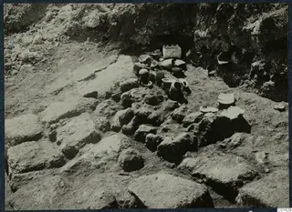Pottery vessels lying in situ among large stone blocks during excavation at Vouni Palace
