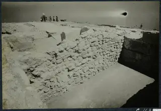 Excavation at Vouni palace showing a rubble wall, a paved surface and a group of people standing on the excavated ground