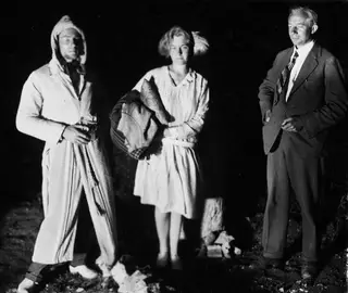 Three people posing outdoors at night at Vouni, one in a striped hooded robe, ready for a moonlight picnic.
