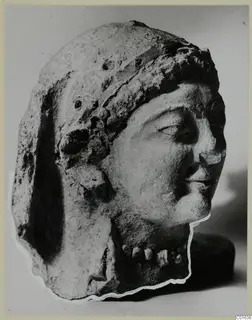 Head of a woman from Vouni in profile view, with a close-fitting headdress and a row of beads at the neck.
