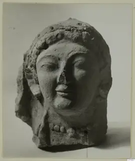 Terracotta head of a female figure with a beaded headdress and a row of beads at the neck, nose broken.