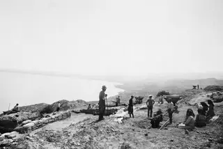 Workers on the eastern slope of the excavation at Vouni, with rail tracks and wagons above the coast.