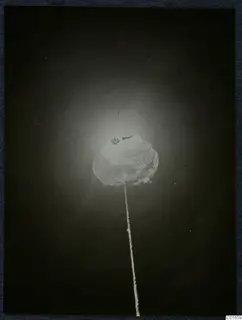 Glowing rounded light hanging on a long string against a very dark background