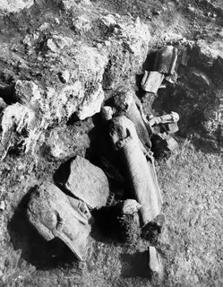 Room 129 at Vouni: broken stone statue fragments lying in situ among rubble and rock in an excavation