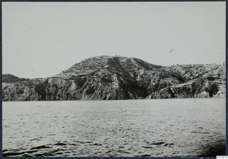 Rocky hill at Vouni rising from the sea, with a few small trees on its crest