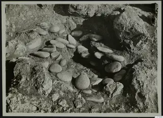 Smooth oval stones set in a curving arrangement among rock outcrops during excavation at Petra tou Limniti.