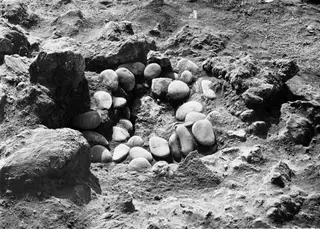 Excavated cut at Petra tou Limniti with a ring of smooth, rounded stones set among boulders and soil