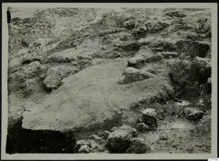 Excavation at Petra tou Limniti with a flat earthen surface and many scattered stones