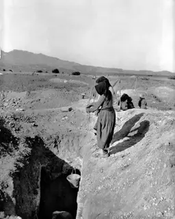 Women working with buckets at the Ayios Iakovos excavation, one hauling a bucket on a rope into a trench