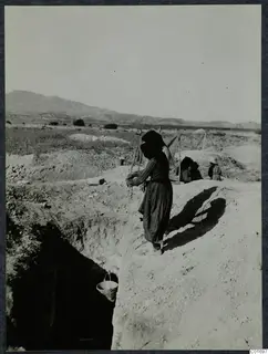 Woman at the edge of a trench at Ayios Iakovos, lowering a bucket on a rope into the excavation
