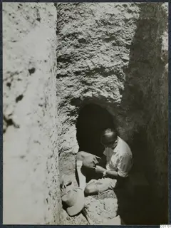 Erik Sjöqvist holding a skull in the dromos to Tomb 8 at Ayios Iakovos