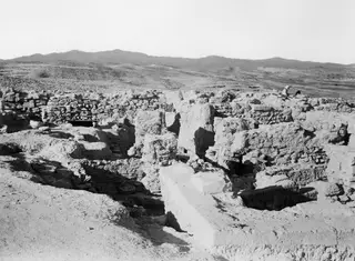 Situation view of excavated stone and earthen walls at Idalion, with a dry landscape and hills behind.
