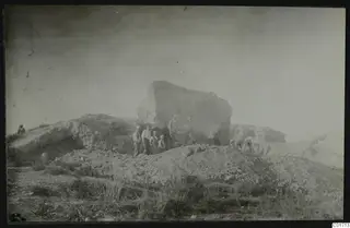 Bamboula cliff from the south during demolition, with a group of men standing in front of the rock face