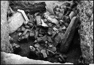 Overview of the large statue deposit at Kition, with broken stone sculptures and blocks packed into an excavation pit.